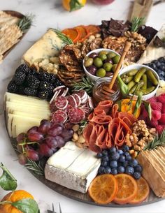 an assortment of cheeses, crackers and fruits are arranged on a platter