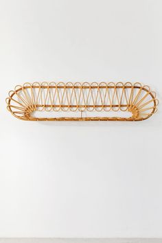 a wall shelf made out of rattan and metal wire on a white wall,