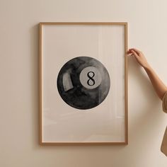 a woman is holding up a black and white 8 - ball print in front of a wall