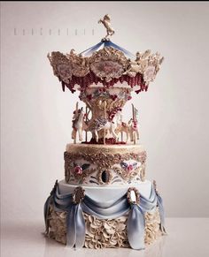 an elaborately decorated carousel cake with blue ribbon around the edges and gold trimmings