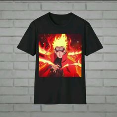 a black t - shirt with the image of naruto on it hanging from a brick wall