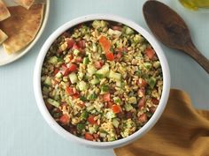 a white bowl filled with rice and vegetables next to a plate of pita bread