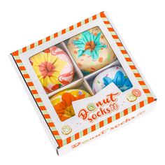 four decorated donuts in an orange and white box