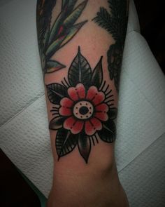 an arm with a flower on it and some leaves around the wrist, in black and red