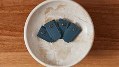 two blue leather tags in a white bowl