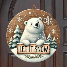 a wooden sign that says let it snow with a polar bear sitting on the front door