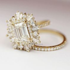 an emerald cut diamond surrounded by smaller round and baguette diamonds on a gold band