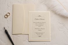 a wedding card with a ring on it next to a pen and feather quill