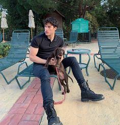 a man sitting on a bench with a dog in front of him and two chairs behind him