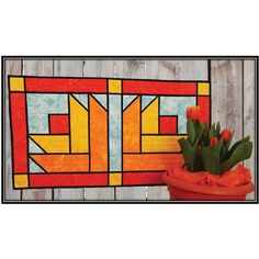 a potted plant sitting next to a stained glass wall hanging on a wooden fence