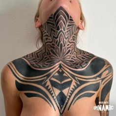 a woman with her face covered in black and white tattoos on her back, looking at the camera