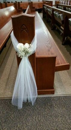 a wedding bouquet sitting on the back of a pew in a church with rows of pews