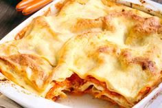 a casserole dish with meat and cheese in it sitting on a wooden table