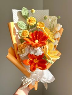 a hand holding a bouquet of flowers with crocheted stems and leaves on it