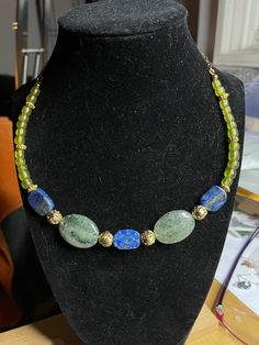 "The ultimate summer necklace: gold beads intersperse the incredible rutile green quartz ovals and the blue pyrite speckled lapis lazuli rectangles. The necklace is finished with hand-made African recycled glass beads. All of the components were obtained from other Etsy shops - helping other small artisan companies in the US also thrive. A really stunning choker, length 18\" to 20\"." Gold Beaded Necklace With Labradorite Stones, Spiritual Green Labradorite Necklaces, Spiritual Green Labradorite Necklace, Handmade Oval Lapis Lazuli Necklace, Green Gemstone Jewelry With Labradorite, Handmade Kyanite Healing Necklaces, Green Labradorite Necklaces With Natural Stones, Handmade Elegant Apatite Necklace, Bohemian Gold Aventurine Necklace