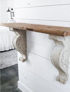 an old wooden shelf with two brackets on it's sides, against a white painted wall