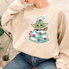 a woman wearing a star wars christmas tree sweatshirt