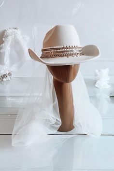 Attention all cowgirl brides-to be! Make your bridal outfit complete with our handmade personalized Bride cowgirl hat. This cream-colored hat features 6-7 rows of gorgeous jewelry and "Bride" or whatever you like, beaded on the top row, letting everyone know who the star of the show is. It's the perfect accessory for your Western-themed wedding or bachelorette party.    What's also great about our hat is that it's customizable to your liking! You can choose the type and color of jewelry used, or Brides With Cowboy Hats, White Cowgirl Hat Wedding, Cowboy Hat With Veil, Cowboy Hat Bride, Bride Cowgirl Hat, Bride Cowboy Hat, Cowgirl Bride, Bachelorette Hats, Hat With Veil