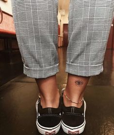 a person wearing black and white checkered pants with tattoos on their feet