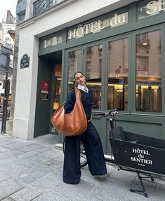 a woman holding a brown bag in front of a hotel