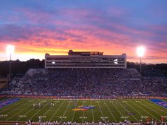 a football stadium filled with lots of people watching the sun go down in the distance