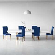 a white table with black chairs and a light hanging from the ceiling