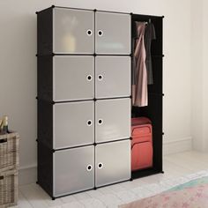 an open closet with several compartments and luggage on the floor next to a bed in a white room