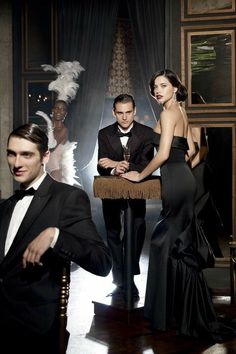 two men in tuxedos and one woman in evening dress posing for the camera