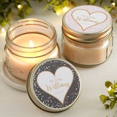 two small jars filled with candles sitting on top of a table