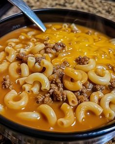 a bowl of macaroni and cheese soup with a spoon sticking out of it