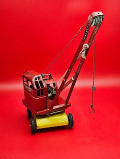 a red and yellow toy truck with a crane on it's back end, against a red background