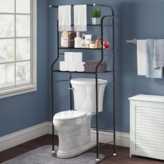 a white toilet sitting next to a metal shelf filled with towels and other bathroom items