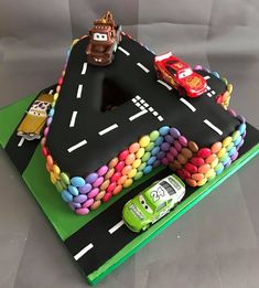 a birthday cake with cars on it and the letter's made out of candy