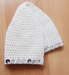 a white knitted hat sitting on top of a wooden table