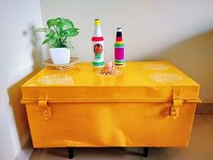 an orange trunk with two bottles on top and a potted plant next to it