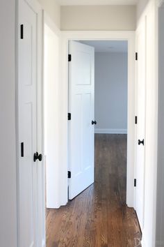 an empty hallway with white doors and wood floors