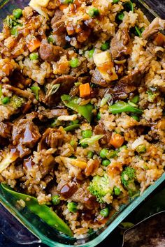 a dish filled with rice, meat and veggies on top of a table