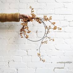 a person holding a bunch of flowers in front of a brick wall with white paint