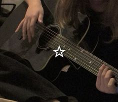 a woman is playing an acoustic guitar in the dark with her hand on the strings