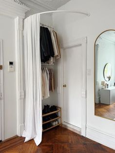 an open closet with clothes and shoes hanging on the door, next to a mirror