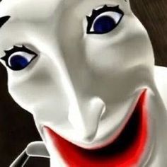 a close up of a white mask with blue eyes and red mouth smiling at the camera