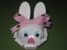 an origami easter bunny mask hanging on a green wall with polka dot ribbon