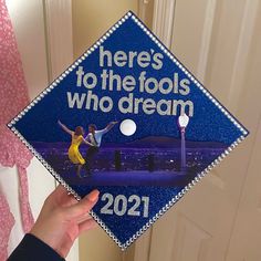 someone holding up a graduation cap that says here's to the fools who dream