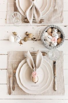 an easter table setting with place settings, napkins and silverware on a white wooden background