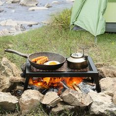 a campfire with pots and pans cooking over it