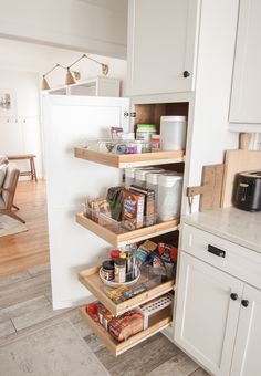 an open pantry door in a kitchen with lots of food on the shelves and drawers