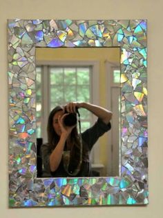 a woman taking a photo with her cell phone in front of a mosaic wall mirror