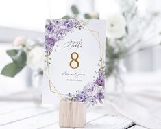 a table number with purple flowers and greenery