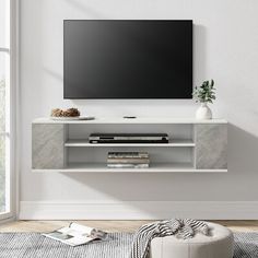 a flat screen tv mounted to the side of a white wall in a living room