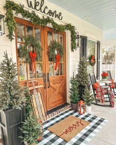 the front porch is decorated for christmas with wreaths and pine trees